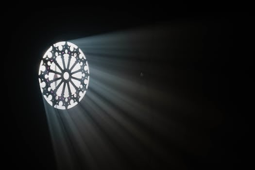 Sunrays shining through an intricate stained glass window in a dark church interior.